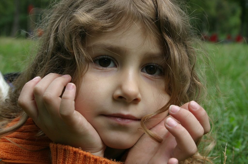 Niña con la cara apoyada en las manos, mirando con atención