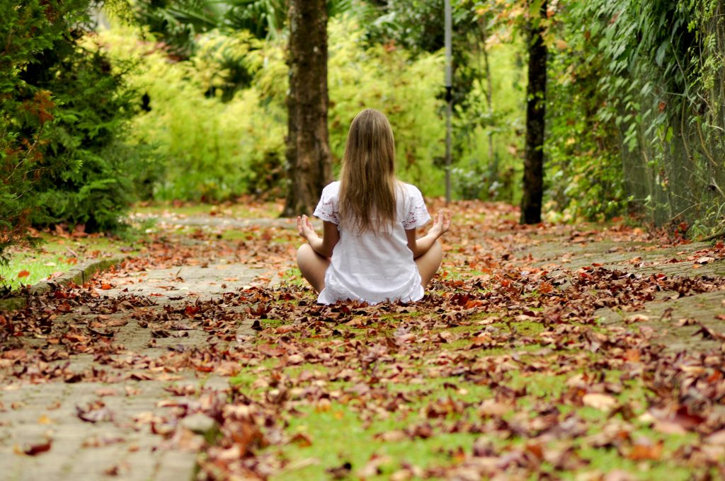 Niña meditando en bosque otoñal