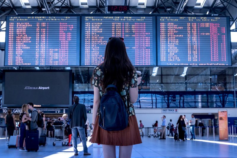 Chica mirando los vuelos anunciados en los paneles de un aeropuerto