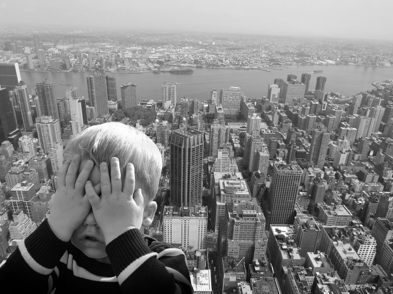 Niño se tapa los ojos en un mirador frente a rascacielos