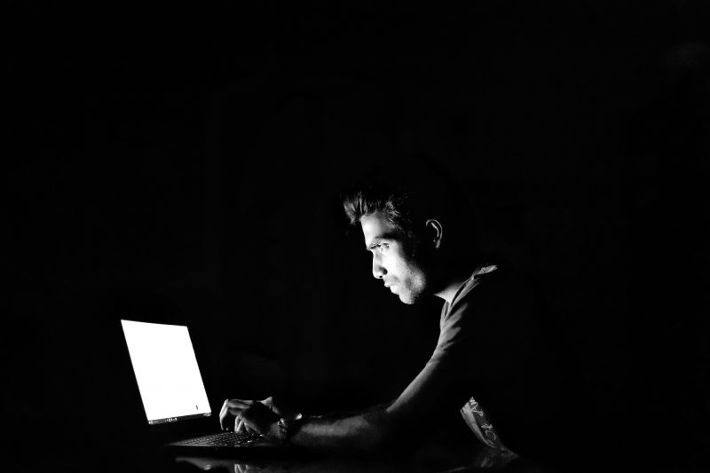 Persona tecleando en el ordenador a oscuras