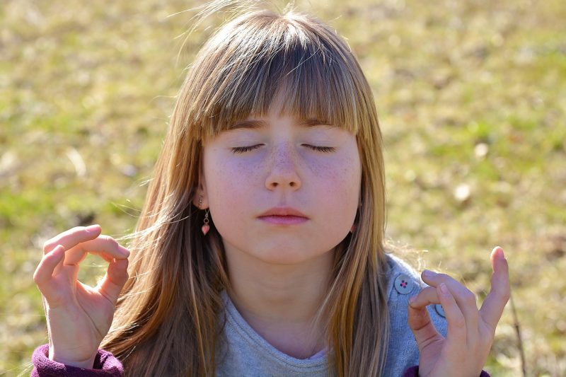 Niña meditando en el campo