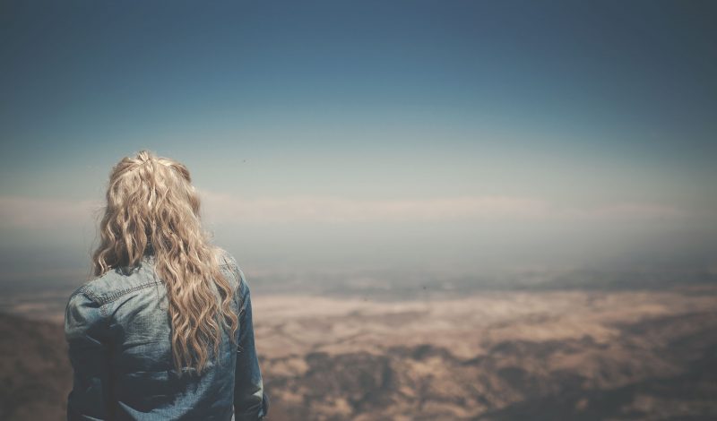 Joven contempla un paisaje desde las alturas.