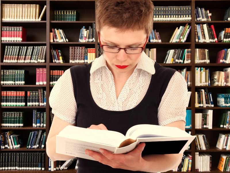 Mujer consulta un libro en biblioteca