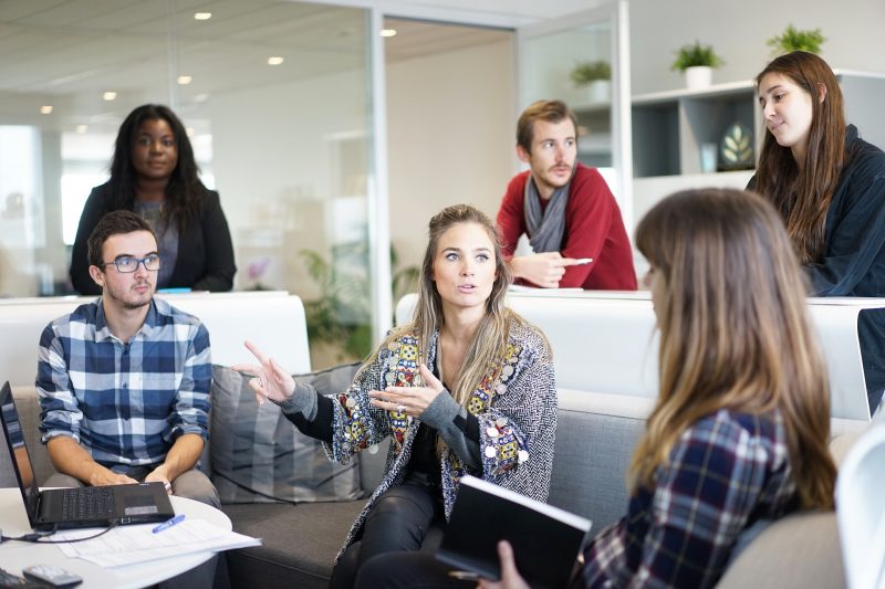 Reunión del equipo de trabajo, varias personas prestan atención a la chica que está hablando