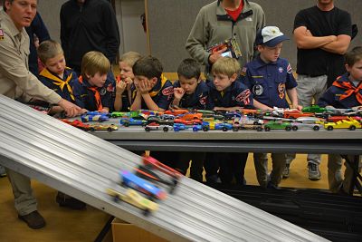 Niños jugando a carreras de coches en interior.