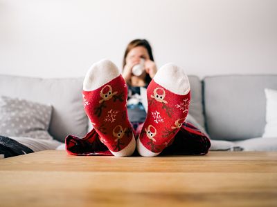 Chica sentada en el sofá con los pies encima de la mesa, una pose que asociamos a menudo a la pereza.